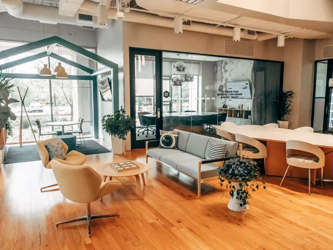 Modern office lounge with seating and glass meeting rooms